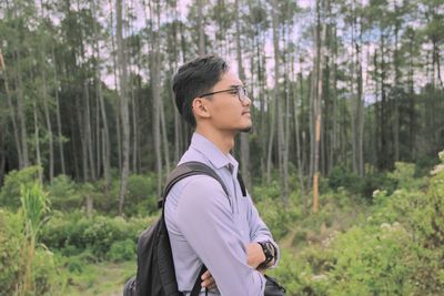 Side view of young man standing in forest