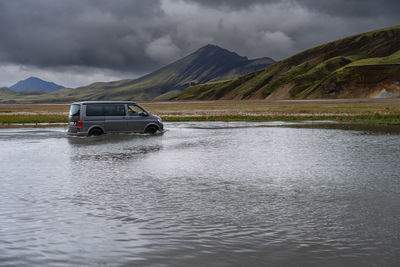 4wd car crossing a river near landmannalaugar campsite in icelandic highlands