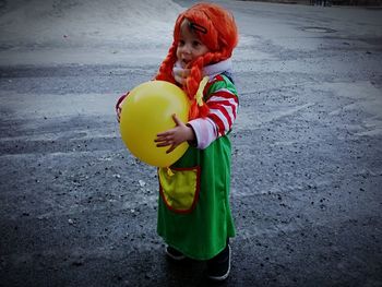 Rear view of girl with umbrella standing on road