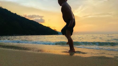 Man standing on beach against sky during sunset