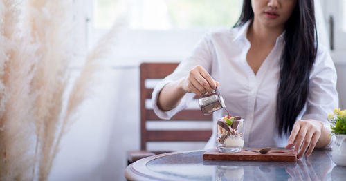 Midsection of woman holding ice cream at home