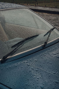 Raindrops over the windscreen and bonnet of a car on a rainy autumn day.