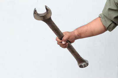 Close-up of person hand holding chain against white background