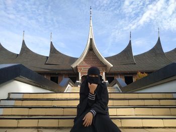 Low angle view of people standing outside building against sky