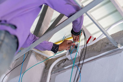 Man works with electrical wires fixing socket at home.