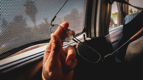 Cropped hand holding eyeglasses in car