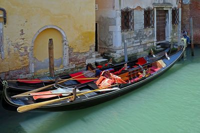 Boats moored in canal amidst buildings