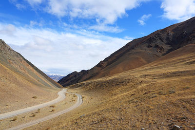 Scenic view of road by mountains against sky