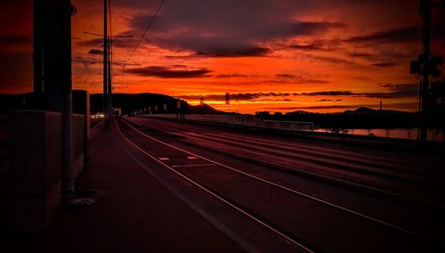 Railroad tracks against dramatic sky during sunset