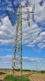 Low angle view of electricity pylon on field against sky