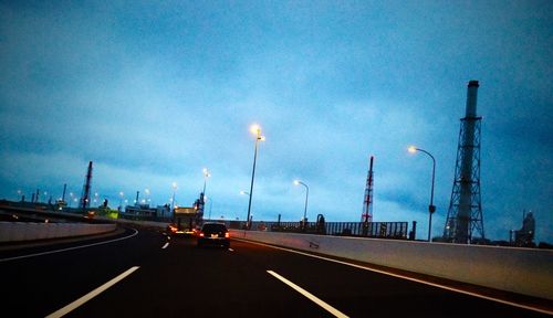 Cars on road against cloudy sky