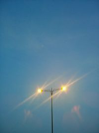 Low angle view of illuminated street light against blue sky