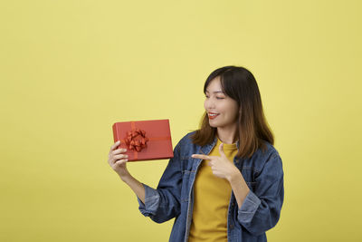 Young woman smiling against yellow background