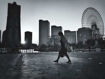 Woman walking on street against buildings in city