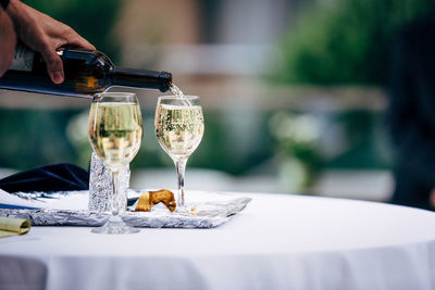 Cropped hand of person pouring drink in glass on table