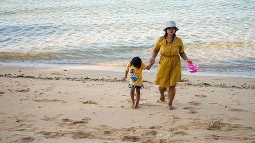 Full length of siblings walking on beach