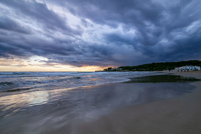 Scenic view of beach against sky at sunset