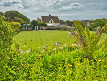 Scenic view of grassy field by building against sky