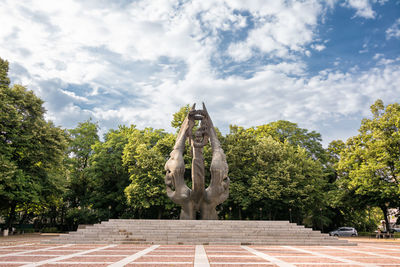 Statue against trees and plants against sky