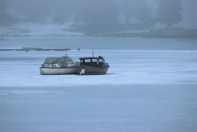 Boat on snow covered landscape against sky