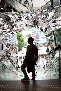 Rear view of man standing at staircase in shopping mall