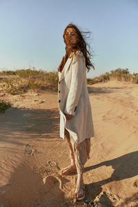 Full length of young woman standing at beach