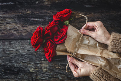 High angle view of hand holding rope tied to wood