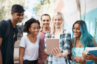 Cheerful friends using digital tablet