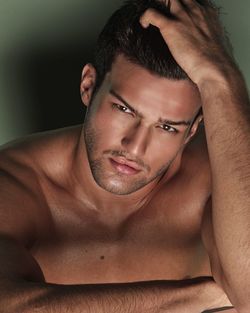 Close-up portrait of handsome young man with hand in hair