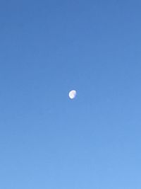 Low angle view of moon against clear blue sky