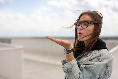 Young woman with arms raised standing against sky