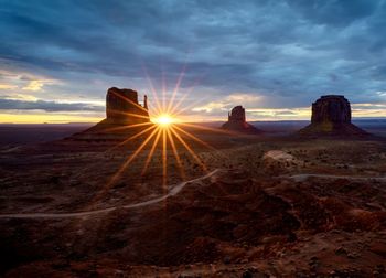 Rear view of man standing on rock against sky during sunset