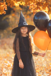 Portrait of young woman wearing hat standing against trees