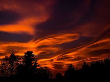 Silhouette trees against dramatic sky during sunset