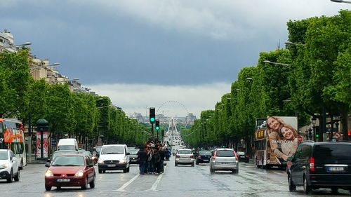 View of city street against cloudy sky