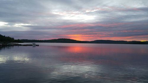 Scenic view of lake against cloudy sky at sunset