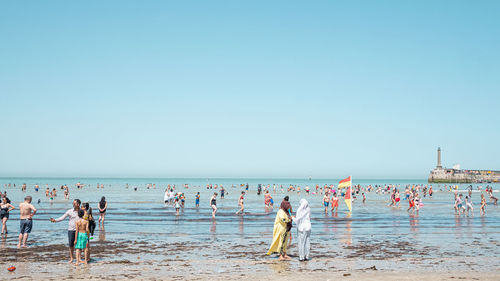 Group of people on beach against clear sky