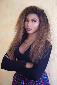 Portrait of beautiful young woman standing against wall