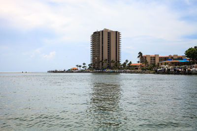 Sea by buildings against sky in city