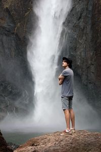 Full length of man standing on rock against waterfall