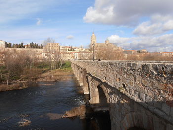 View of old building by river against cloudy sky