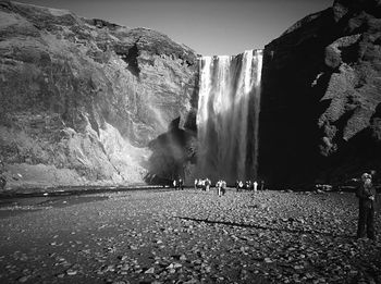 Panoramic shot of people at waterfall against sky