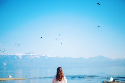 Rear view of woman overlooking calm lake