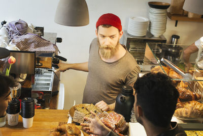 Man talking to barista at cafe counter