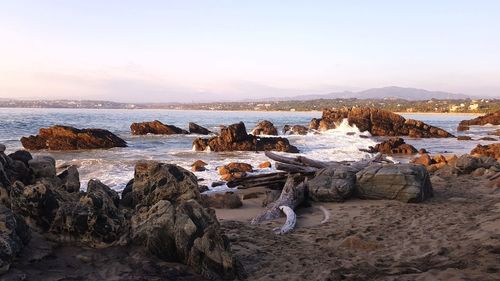 Rocks on beach against sky during sunset