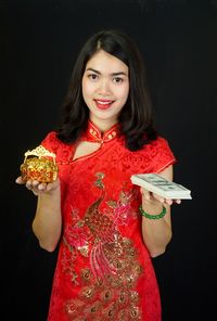 Portrait of smiling woman standing against black background