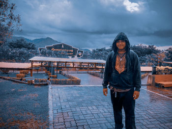 Portrait of young man standing in rain outdoors