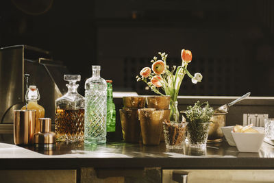 Alcohol bottles with flower vase on table