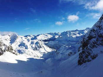 Scenic view of snow covered mountains against blue sky