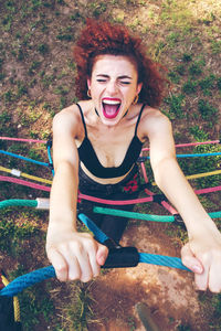 High angle view of woman shouting while climbing on rope at playground